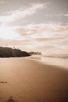 A peaceful beach scene at sunset with gentle waves and cloudy sky.