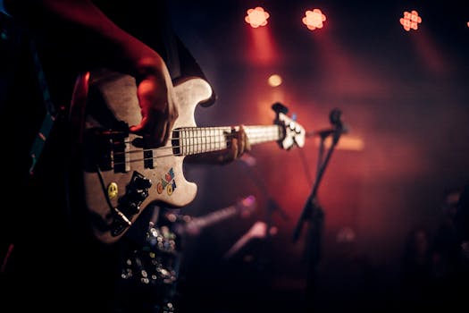 Dynamic image of a guitarist playing at a live music concert, illuminated by colorful stage lights.