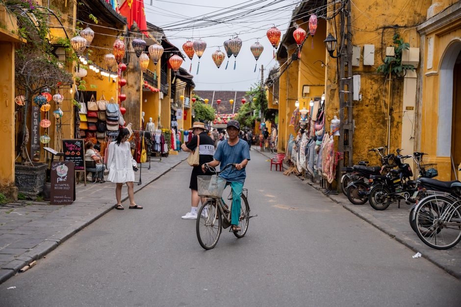 Traditional street in Vietnam with vibrant lanterns and a cyclist, captured in an urban setting.