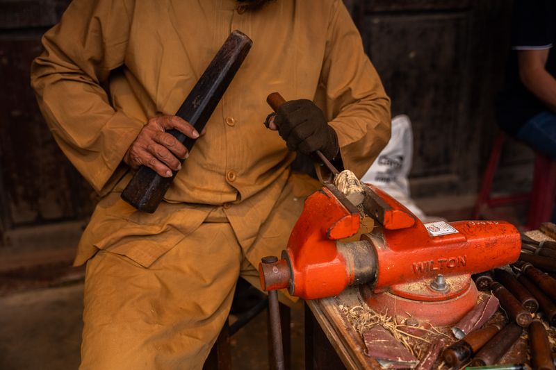 A focused craftsman using a chisel and vise for detailed wood carving. Capturing the essence of traditional woodworking.