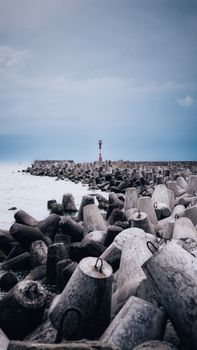 Concrete blocks line a coastal breakwater under overcast skies, protecting against sea waves.
