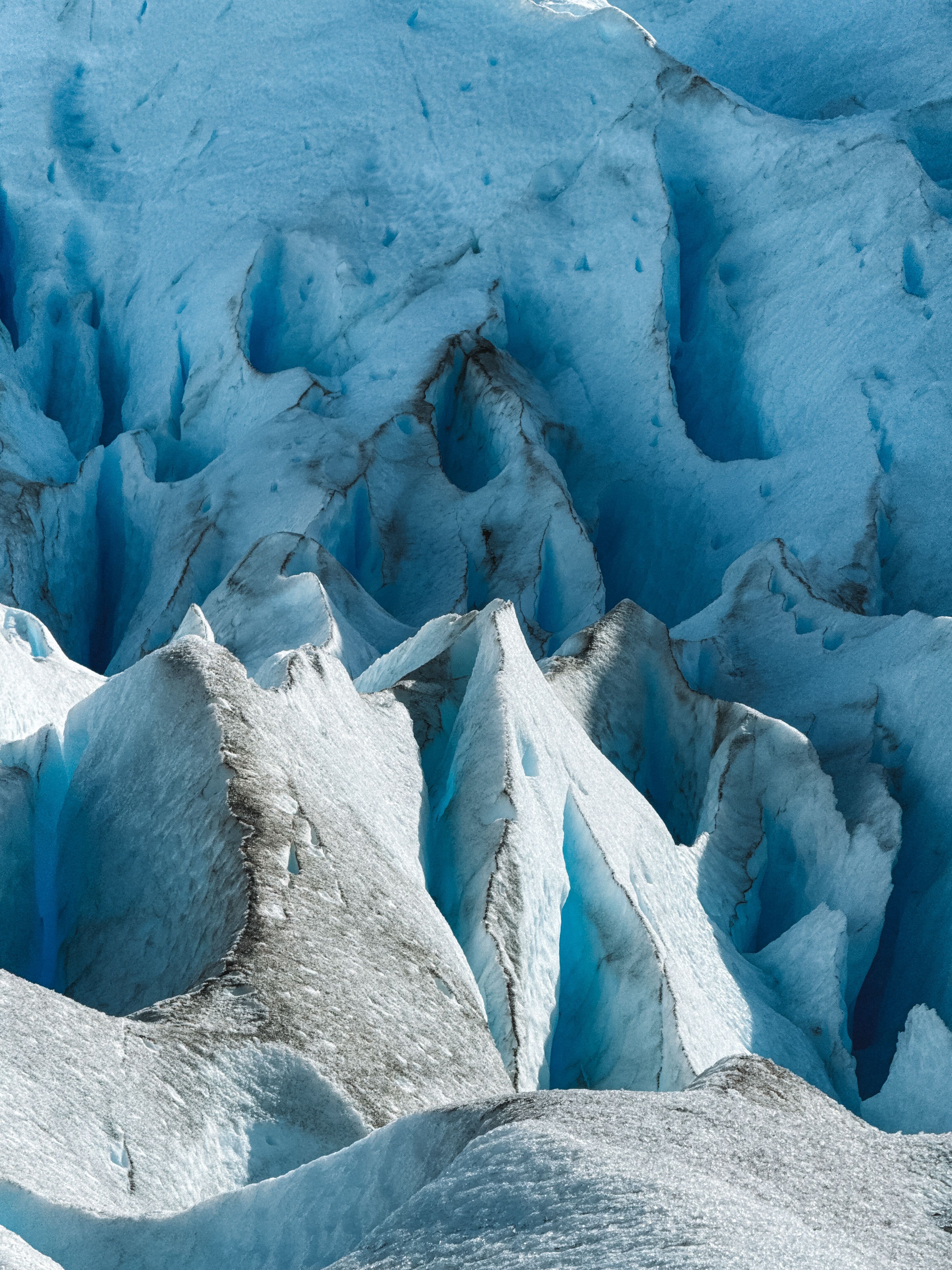 Scientists on a snowfield measuring ice depth with equipment near a glacier margin