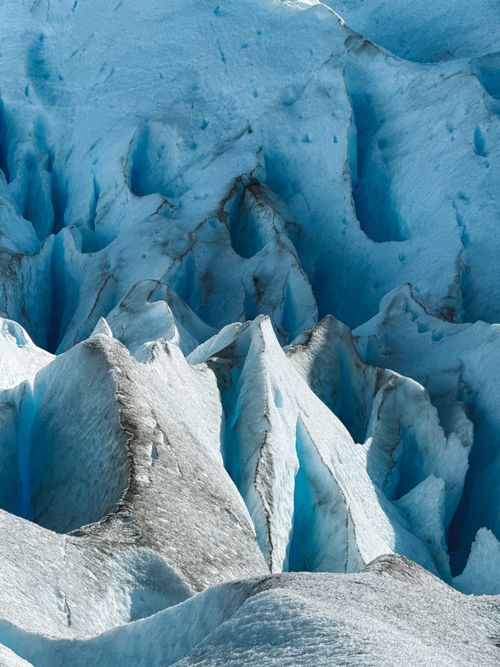 Scientists on a snowfield measuring ice depth with equipment near a glacier margin