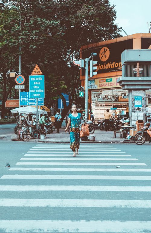Free A woman walks confidently across a city crosswalk surrounded by urban activity and signage. Stock Photo