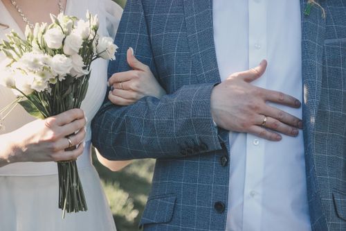 Free Close-up of a couple in formal attire holding a bouquet on their wedding day. Stock Photo