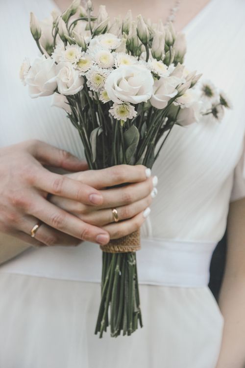 Free Close-up of a bride holding a delicate white bouquet, showcasing wedding rings. Stock Photo