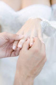 Close-up of hands during a wedding ring exchange, symbolizing love and commitment.