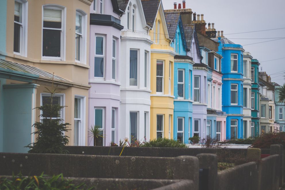 Row of pastel-coloured terraced houses along a quiet residential street, photo by Connor Danylenko on Pexels