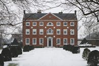 一座优雅的砖砌大厦矗立在白雪皑皑的冬季景色中，展现出经典的建筑细节与庄严的对称性