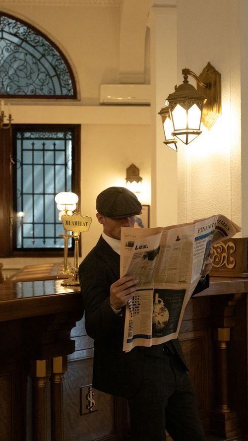 Free A man in elegant attire reading a newspaper in a vintage interior, creating an old-fashioned, sophisticated scene. Stock Photo