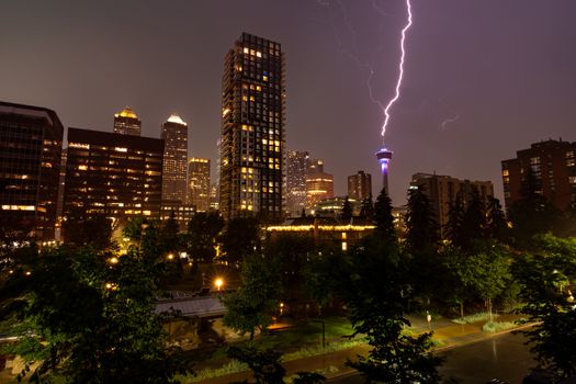 Dramatic thunderstorm with lightning illuminating the Calgary skyline. Urban nightscape with skyscrapers and the Calgary Tower.