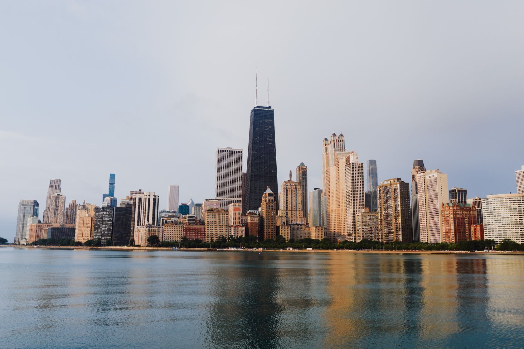 Stunning view of Chicago's skyline with calm waterfront reflections under a clear sky.