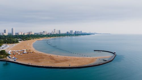 Free Scenic aerial view of Chicago's coastline with sandy beach and urban skyline under a cloudy sky. Stock Photo