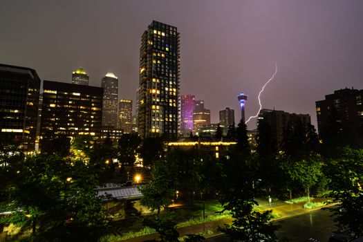 Dramatic Calgary cityscape at night with striking lightning, highlighting modern architecture and landmarks.