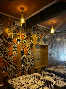 A colorful mosaic-tiled wall in a stylish restaurant with ambient lighting and neat seating arrangement.