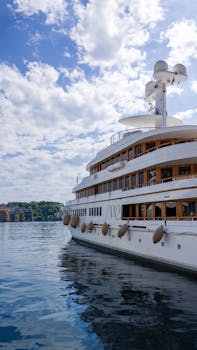 Elegant yacht docked in Monaco under a bright, cloud-dotted sky, perfect for travel inspiration.
