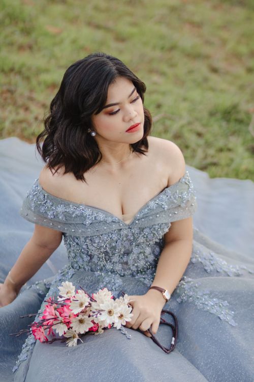 Free Beautiful woman in an elegant gray gown holding a bouquet outdoors. Stock Photo