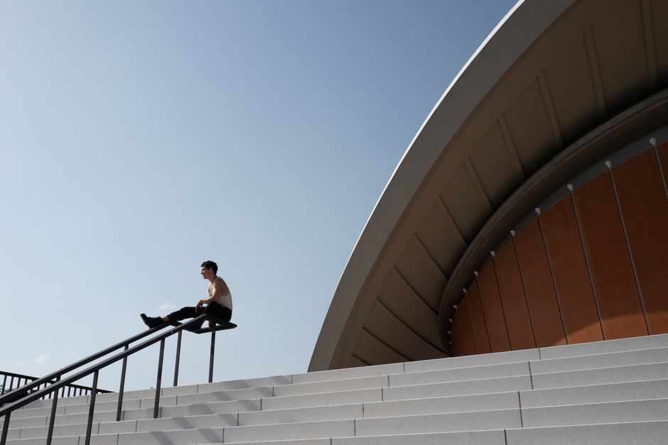 ドイツ、ベルリンの現代建築物の階段に座っている若い男性。