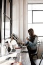 Woman in Gray Jacket Sitting Beside Desk