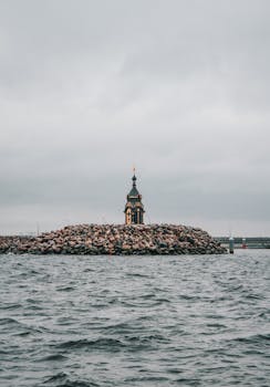 A serene chapel on a rocky island amidst cloudy skies in St Petersburg, Russia.
