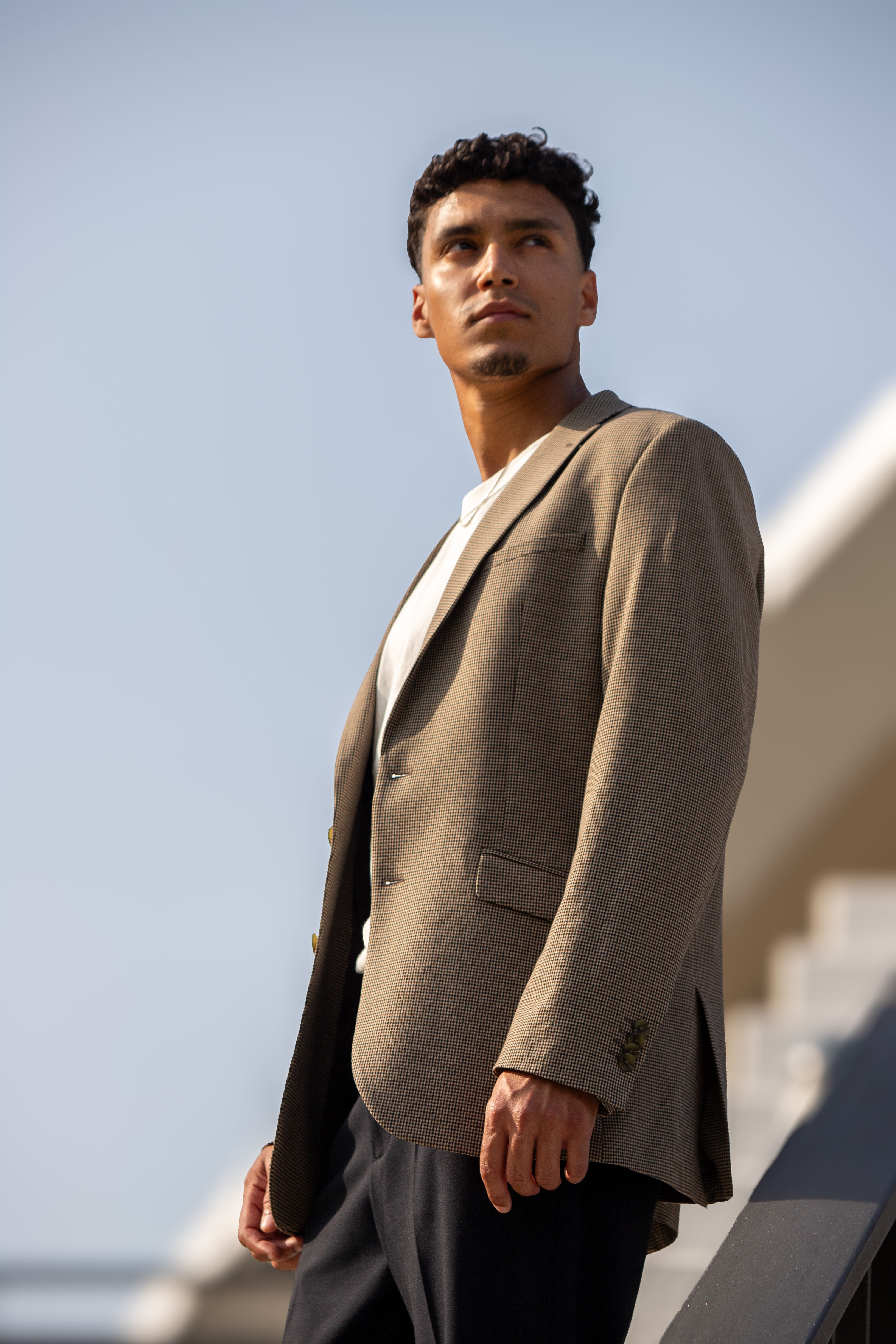 Stylish male in a jacket poses confidently outdoors in Berlin's urban landscape.