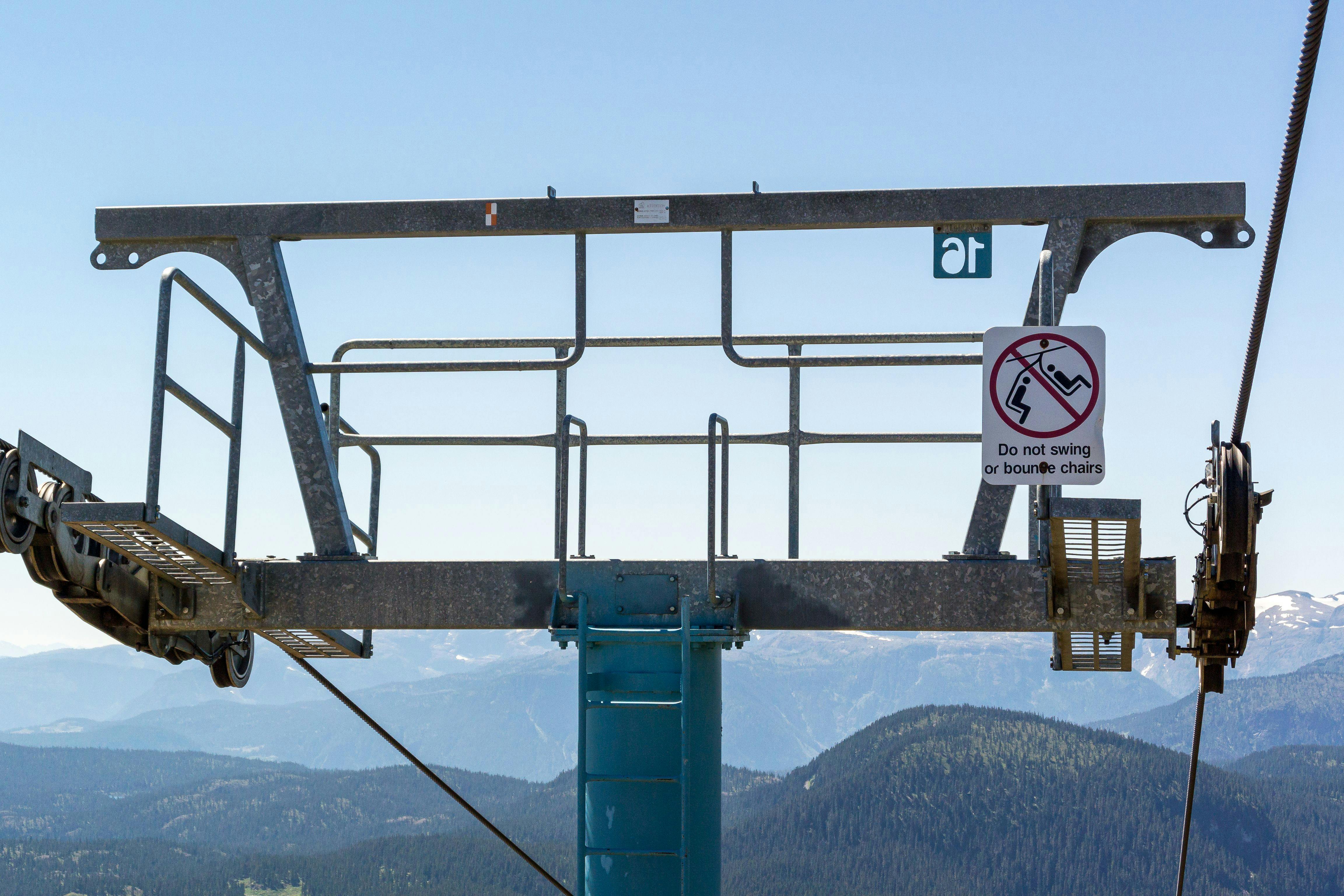 Prescription Goggle Inserts - Steel chair lift structure against a scenic mountain backdrop on a clear day.