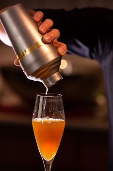 充满活力的鸡尾酒从摇床倒入室内鸡尾酒杯的特写