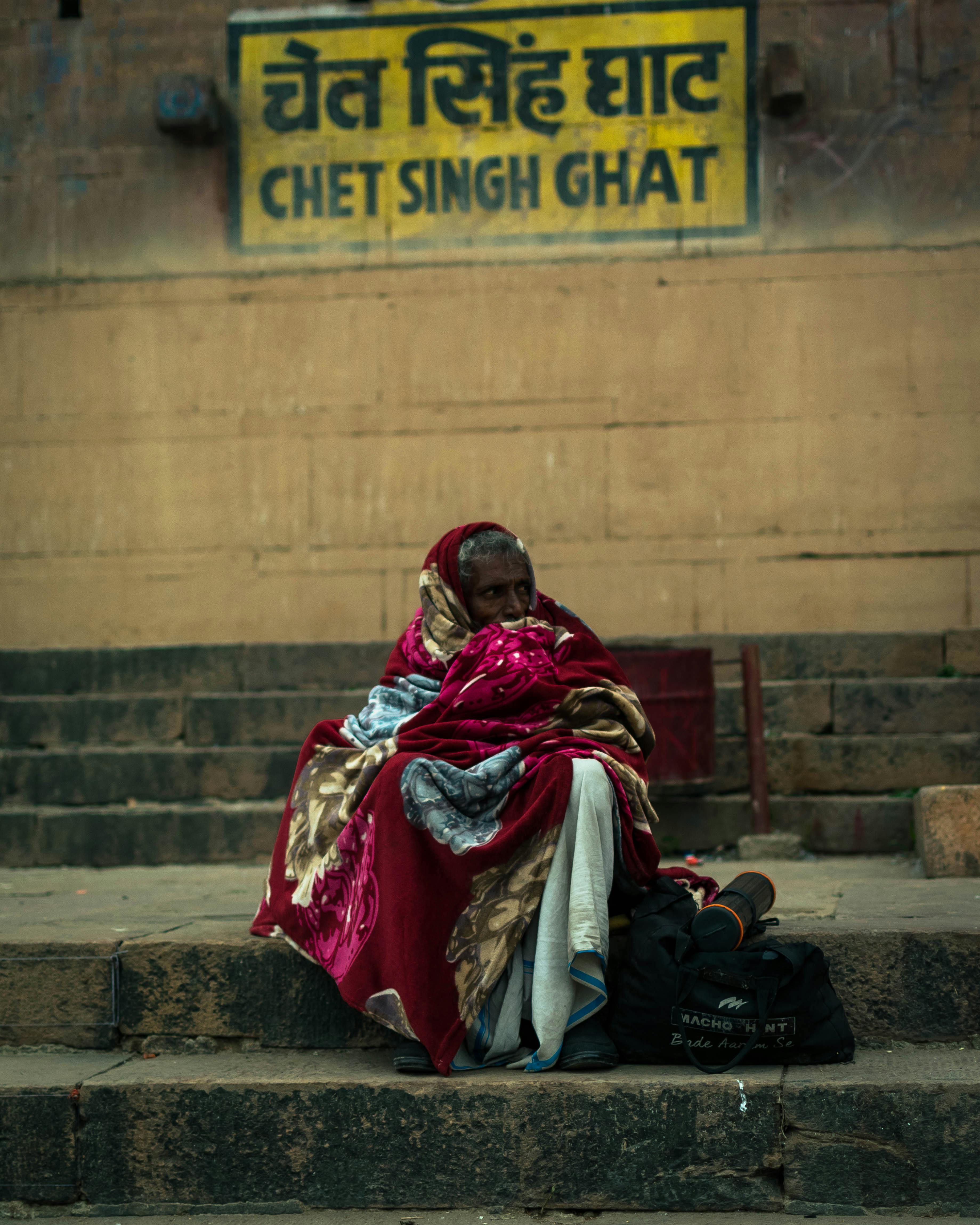 Elderly Indian woman wrapped in a sari seated at Chet Singh Ghat, Varanasi, India.