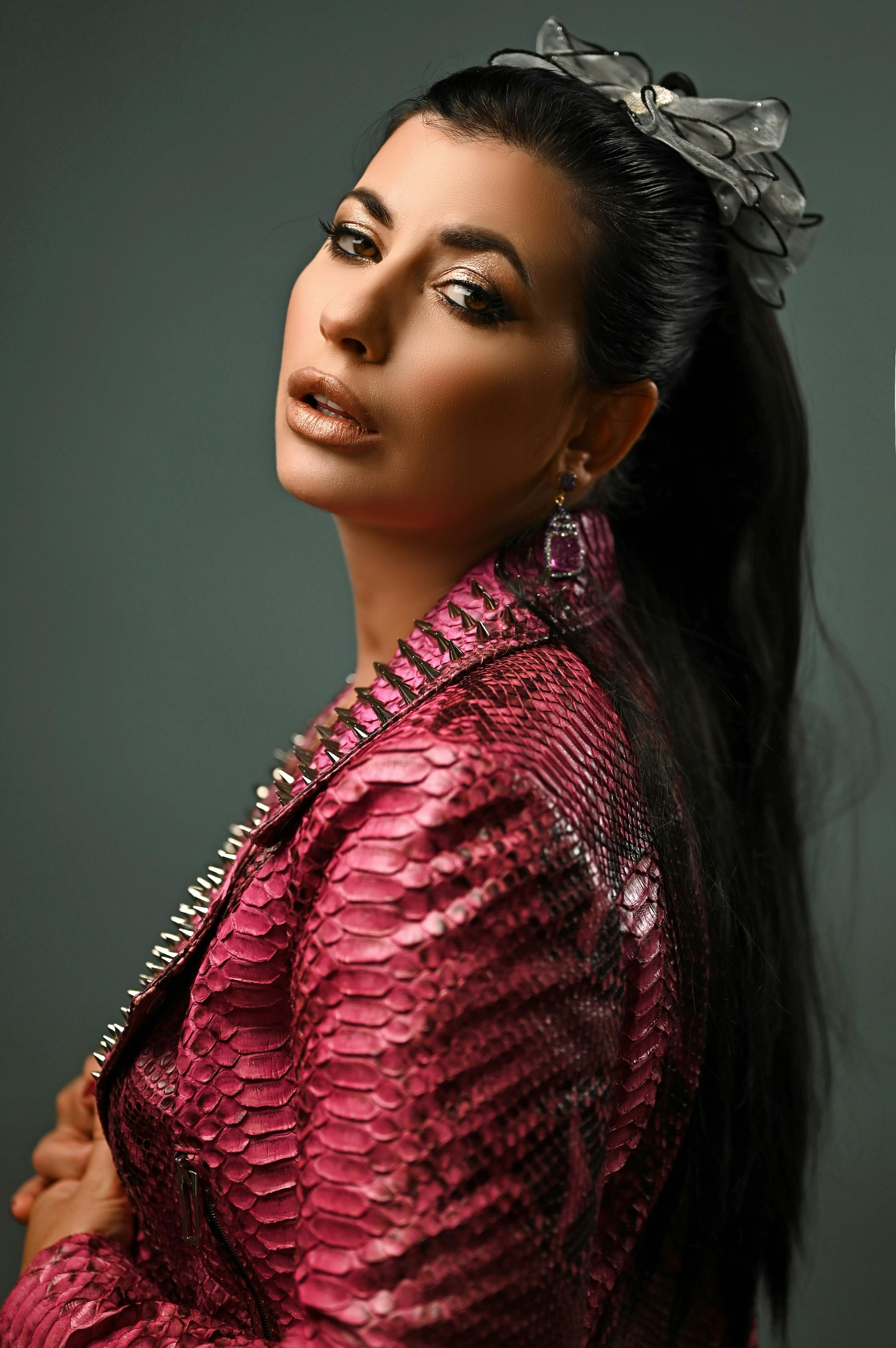 Chic studio portrait of a woman in a stylish pink snakeskin jacket focusing on contemporary fashion.