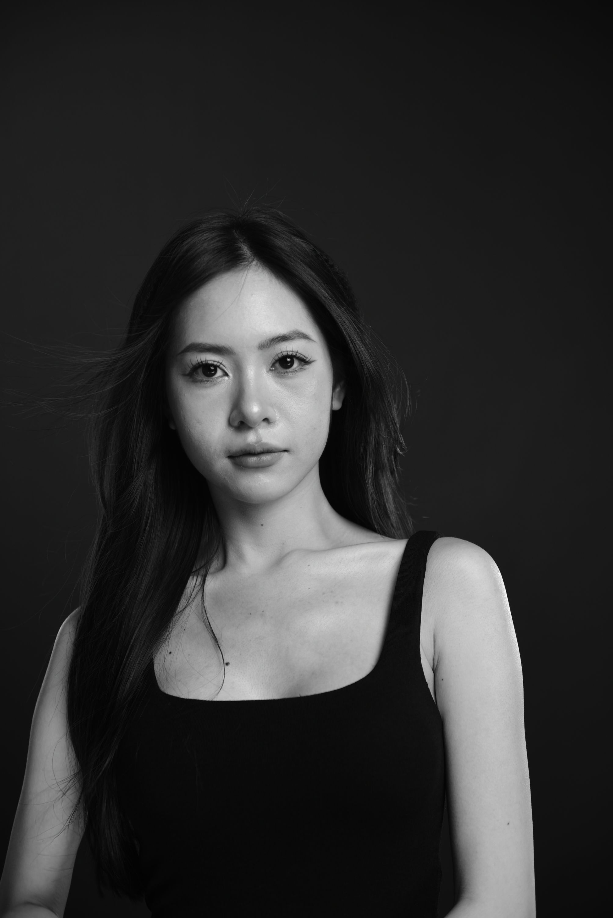 Black and white portrait of a woman with long hair in a studio setting.