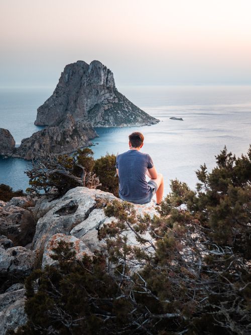 Free A man enjoys a peaceful moment overlooking the sea and island, capturing serene natural beauty. Stock Photo