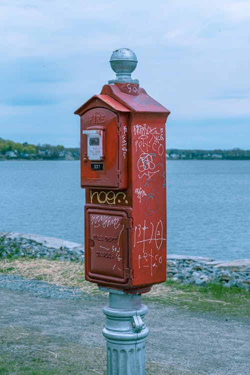 Photo of Red and Gray Metal Mailbox Near Body of Water