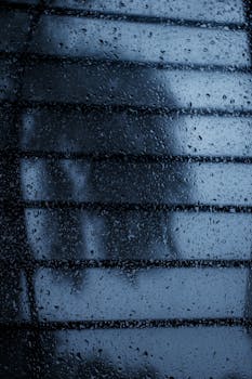 Abstract view of water droplets on glass, showcasing a rainy and moody ambiance.