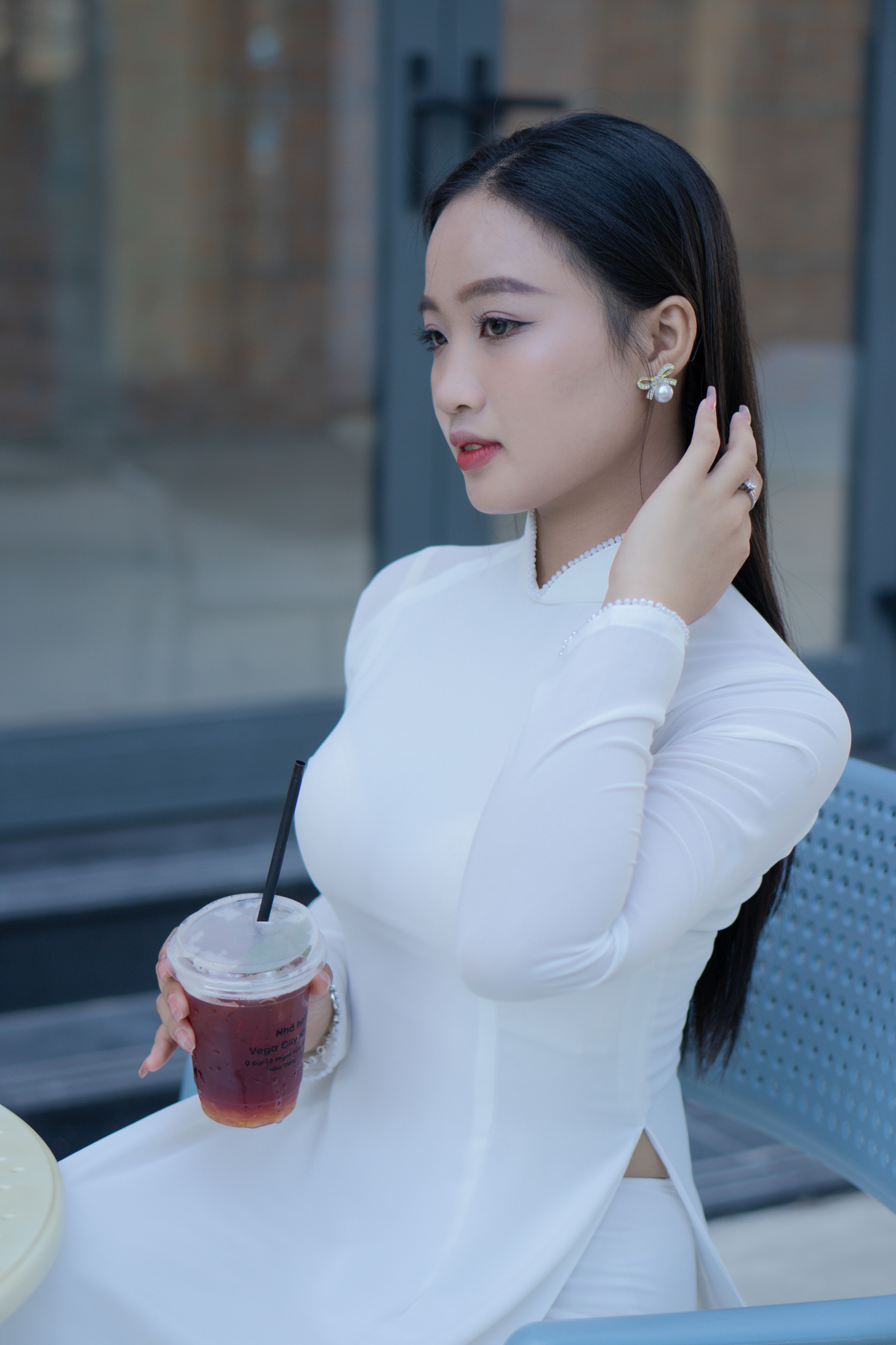 A Young Woman in a White Ao Dai Sitting at a Table · Free Stock Photo