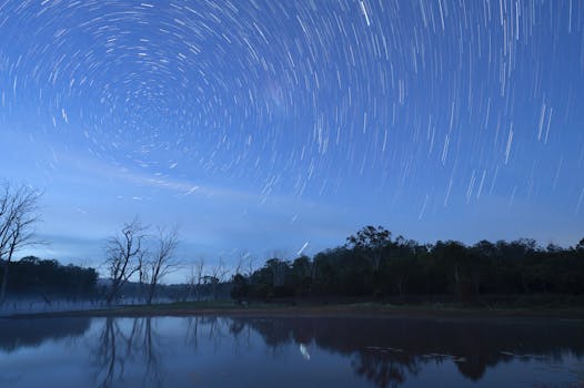 Stunning star trails create a swirling night sky over a serene pond in Queensland, Australia.