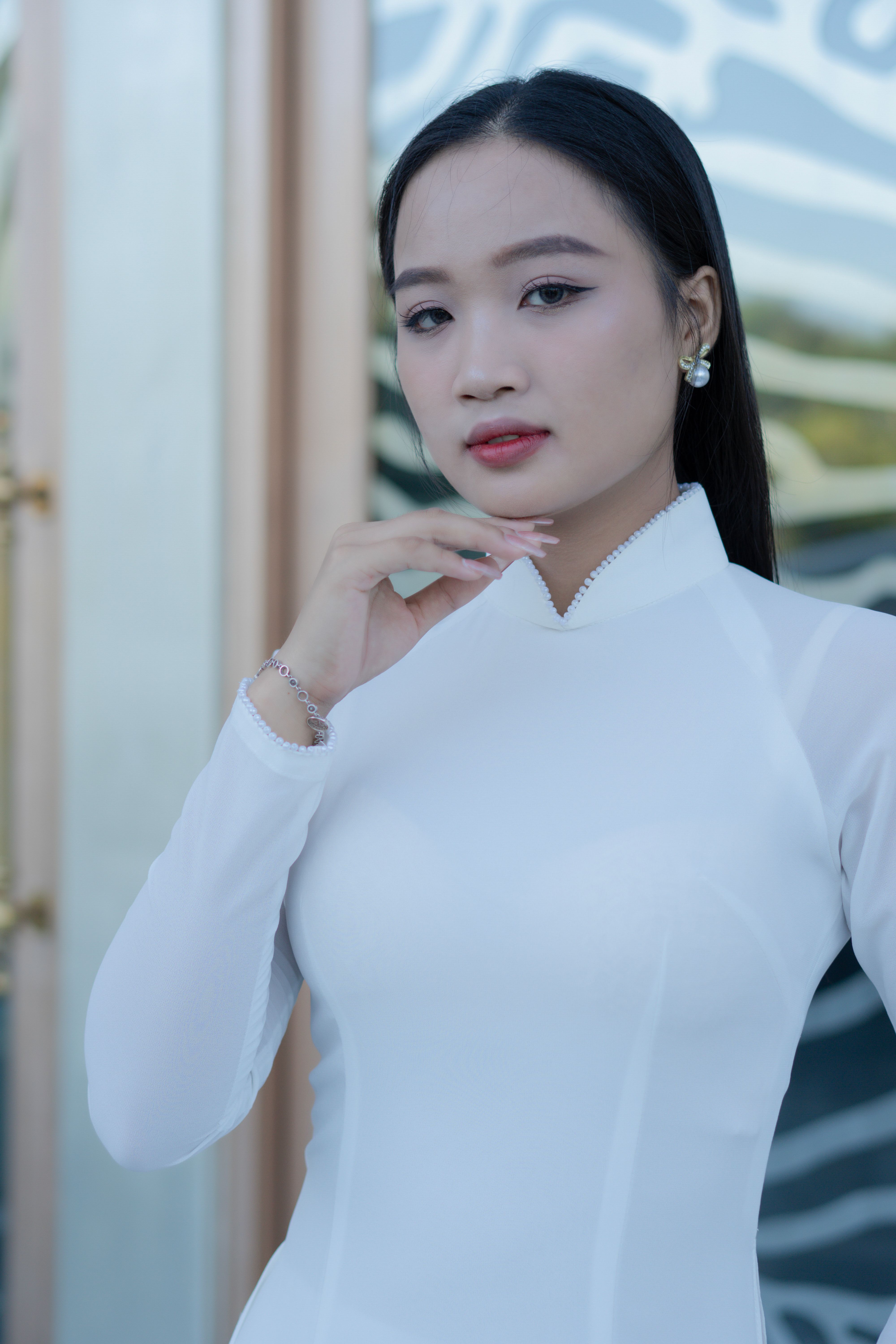 An elegant portrait of an Asian woman in traditional Ao Dai clothing, posing gracefully indoors.