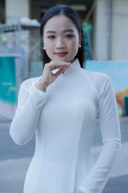 Portrait of an Asian woman in traditional Ao Dai, standing outdoors.