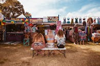 阳光明媚的一天，穿着时髦的女性在狂欢节摊位旁享受节日的明亮场景