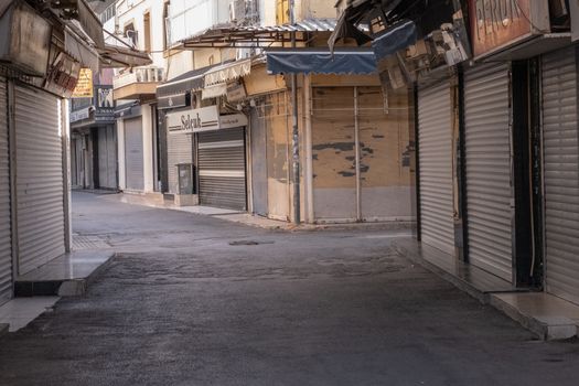 A deserted street in İzmir, Türkiye, lined with closed shops and shuttered storefronts.