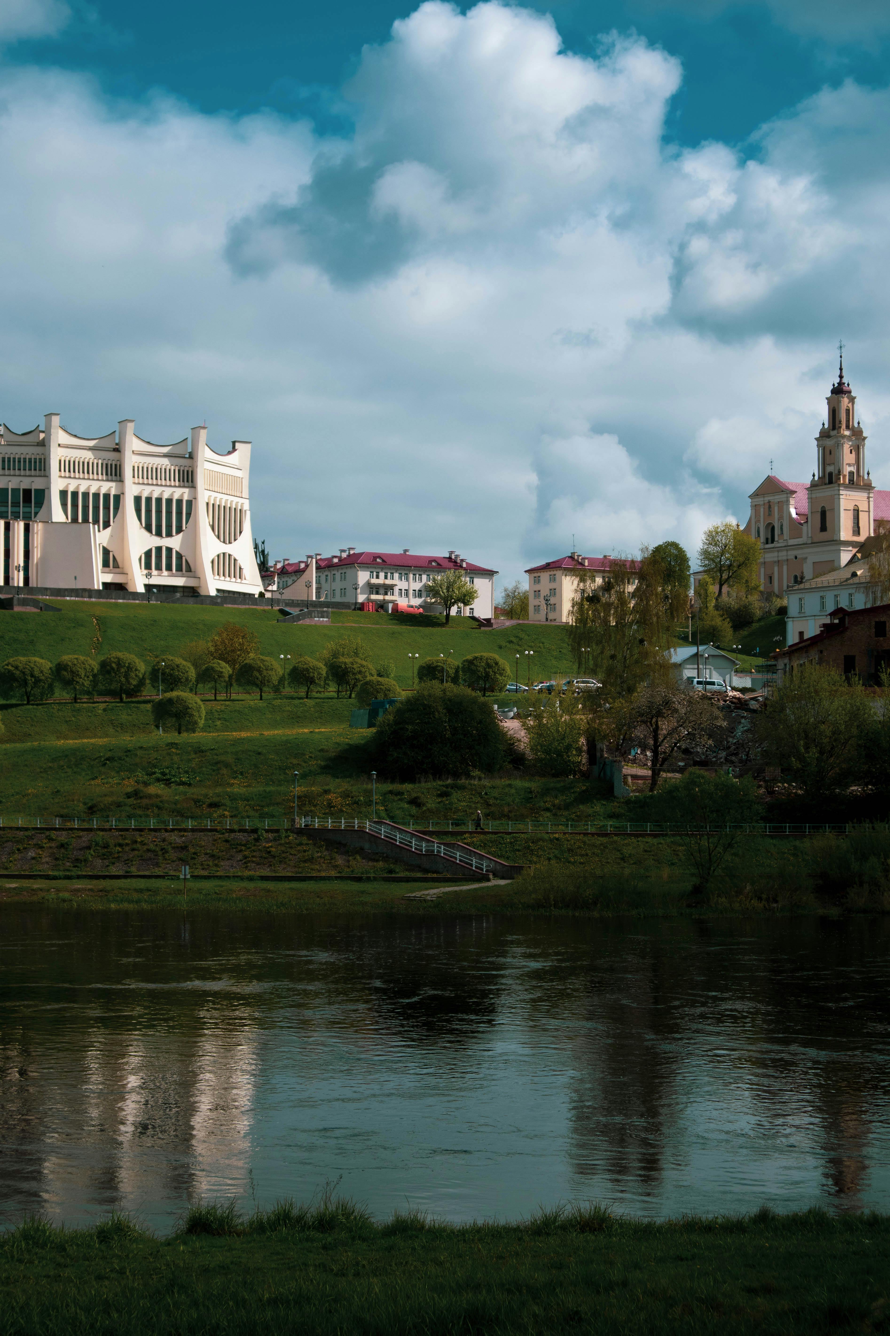 Captivating view of Grodno's dramatic architecture and riverside greenery under a dramatic sky.