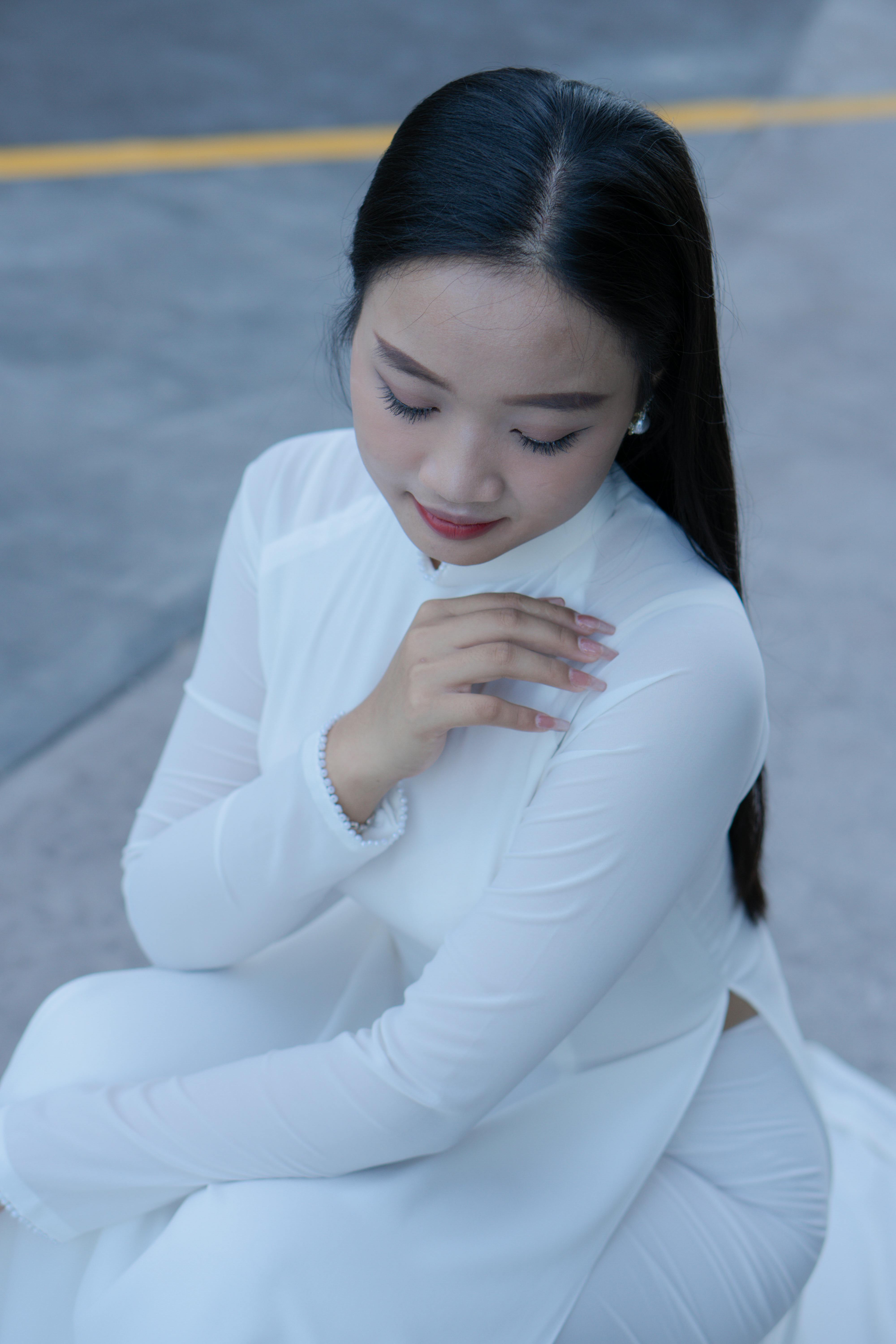 A portrait of an Asian woman wearing a traditional white ao dai, captured with a serene expression.