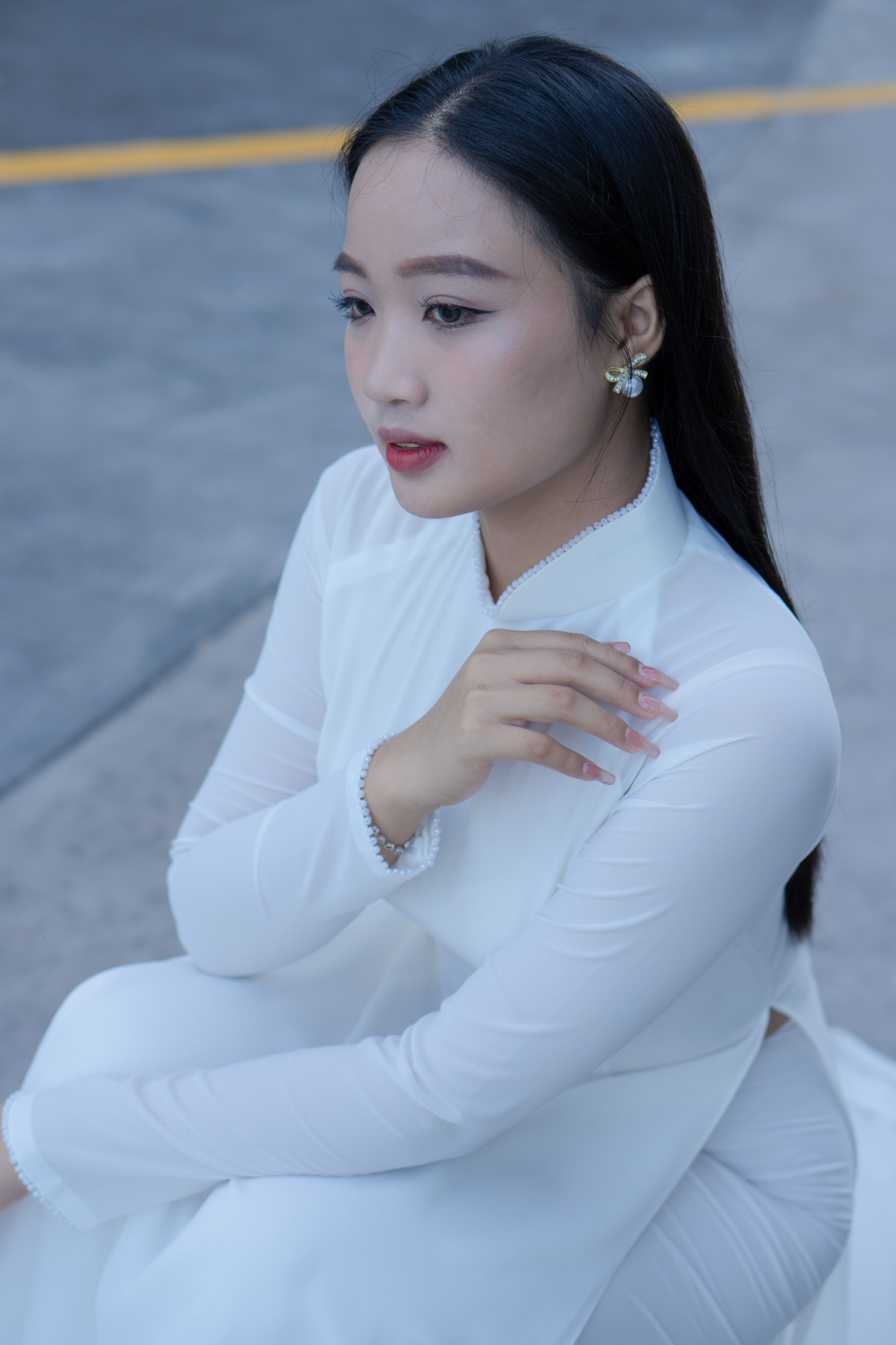 Portrait of an Asian woman seated in a white ao dai, showcasing elegance and tradition.