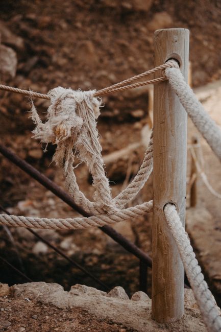 Weathered rope tied around wooden post, showcasing rustic and rural textures.