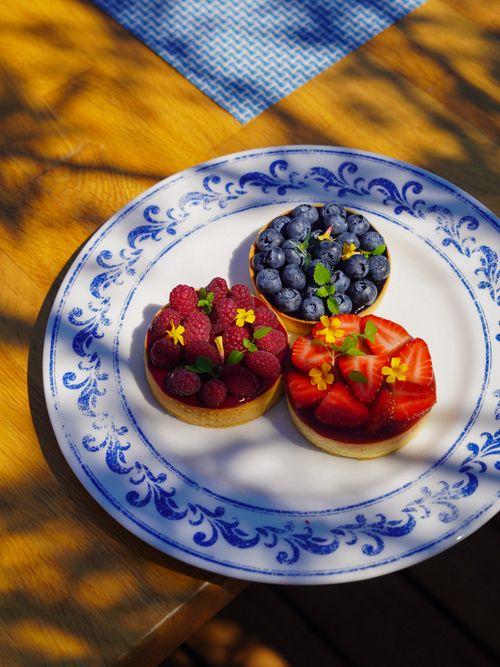 Free Colorful fruit tartelettes with strawberries, raspberries, and blueberries on a ceramic plate. Stock Photo