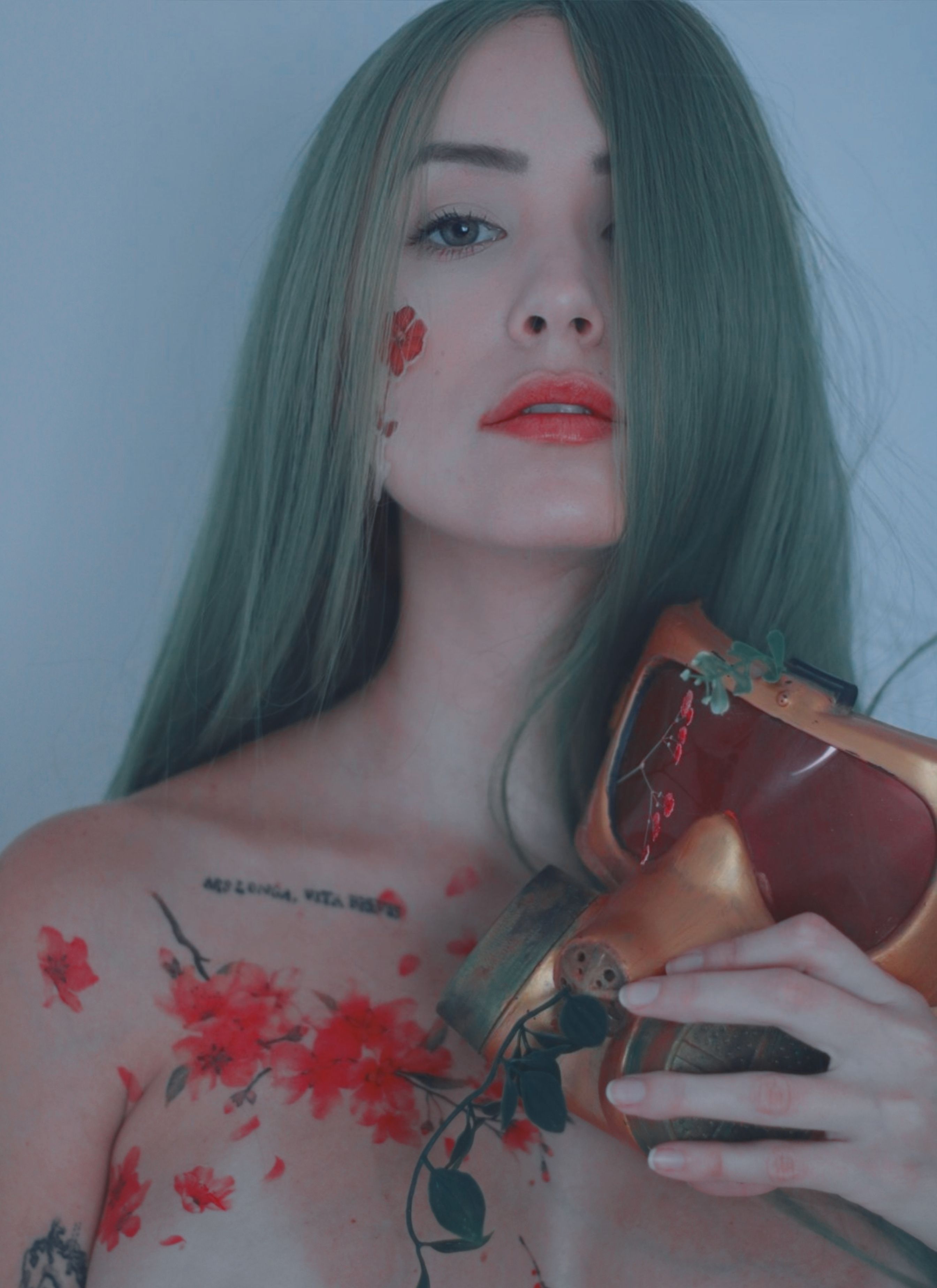 A creative photo of a woman with turquoise hair, gas mask, and floral tattoos, showcasing a unique artistic expression.
