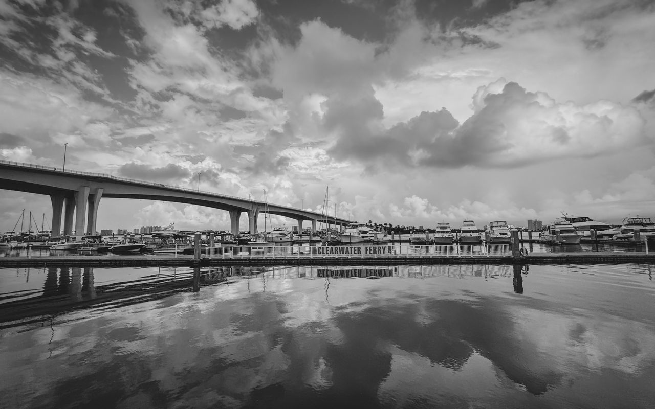 Monochromatic view of Clearwater harbor with bridge and boat reflections.