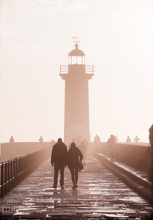 Two People Walking Near Lighthouse