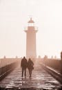 日落时分，一对夫妇走向灯塔的浪漫场景，轮廓和大气的灯光