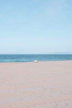 A tranquil beach scene featuring calm ocean and clear sky.
