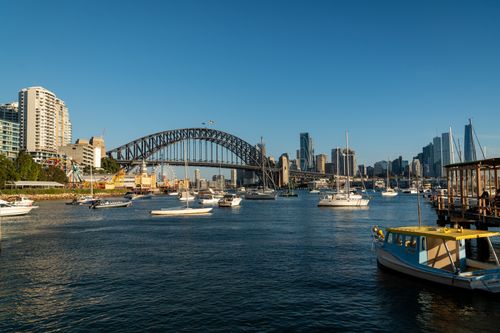 Free A picturesque view of Sydney Harbour Bridge with boats and skyline under clear blue sky. Stock Photo
